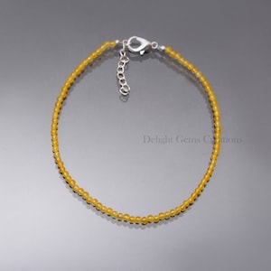 May include: A delicate yellow gemstone bracelet with a silver clasp. The bracelet is made of small, round beads and is approximately 18 cm in length.