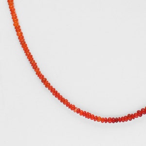 May include: A necklace made of small, round, orange carnelian beads.