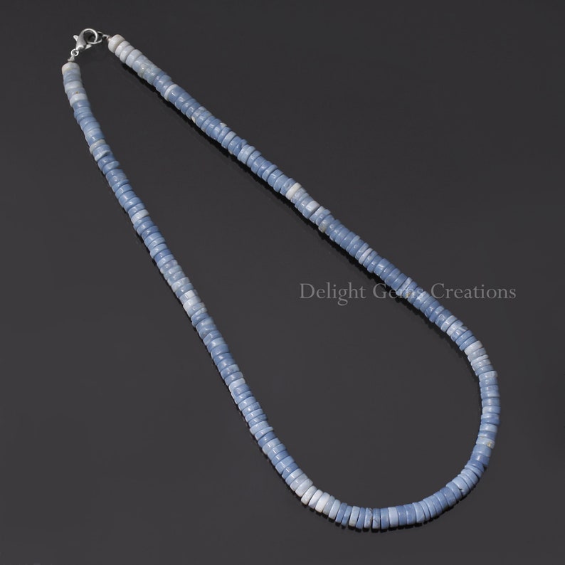 May include: A light blue opal beaded necklace with a silver clasp. The necklace is made of small, round beads that are strung together to create a long, flowing strand.