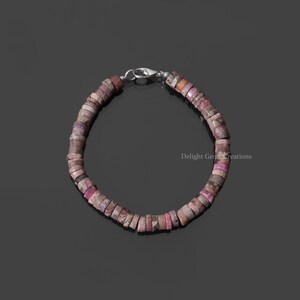 May include: A pink and white gemstone bracelet with a silver clasp. The bracelet is made of small, round beads.