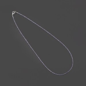 May include: A silver chain necklace with small, light purple beads.