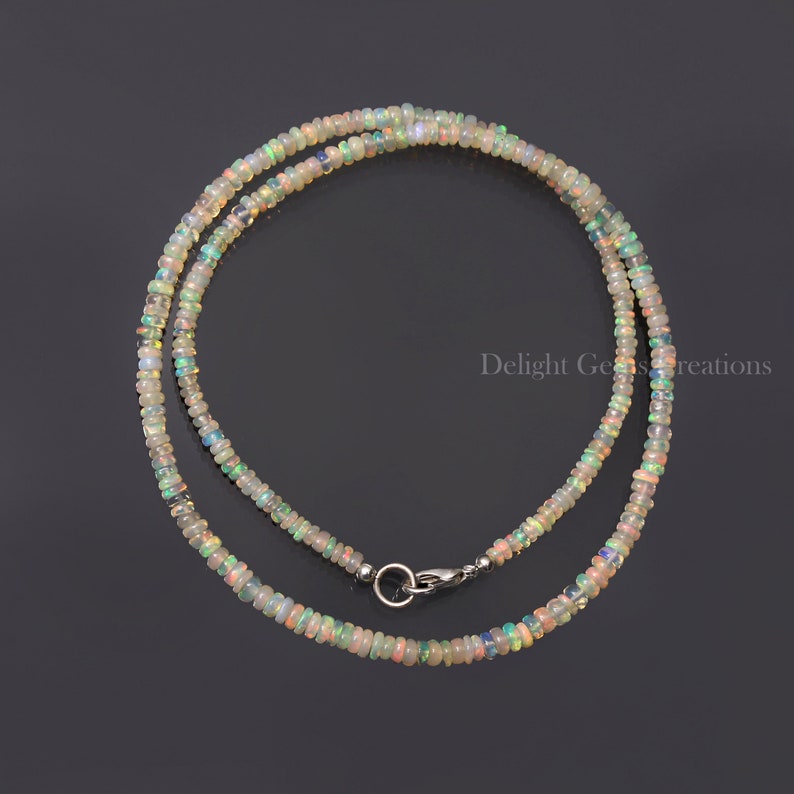 Puede incluir: Un collar delicado hecho con peque&ntilde;as cuentas de &oacute;palo iridiscente. El collar es de color plateado y tiene un cierre de mosquet&oacute;n.