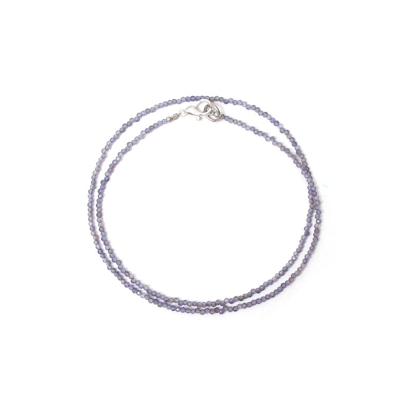 May include: A delicate silver chain necklace with small, light purple beads. The necklace is layered and has a silver clasp.