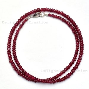 Op de afbeelding: Een dubbele ketting van kleine, ronde, rode robijn kralen. De ketting is ongeveer 45 cm lang en heeft een zilveren sluiting.