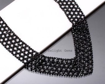 May include: A multi-strand black beaded necklace, composed of small, faceted beads. The necklace is presented on a white and grey surface. The text "Delight Gems" is visible in the image.