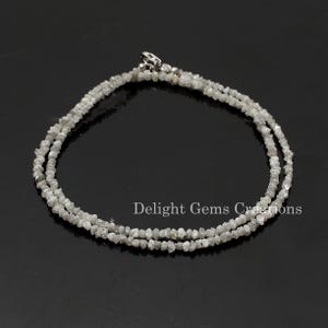 May include: A silver chain necklace made with rough, white diamonds. The necklace is double-stranded and has a silver clasp.