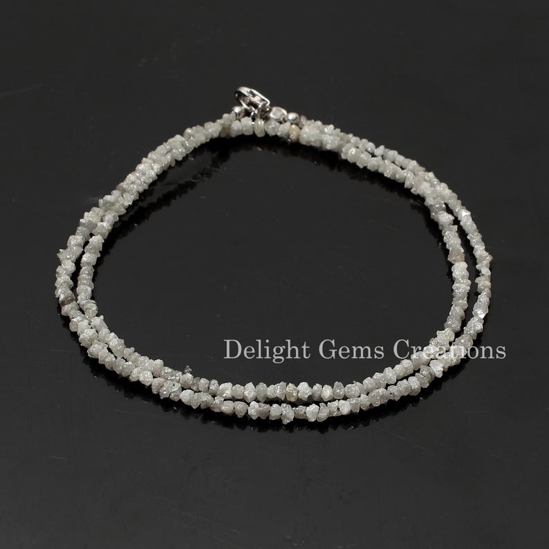May include: A silver chain necklace made with rough, white diamonds. The necklace is double-stranded and has a silver clasp.