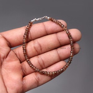 May include: A brown gemstone bracelet with a silver clasp. The bracelet is made of small, faceted beads.