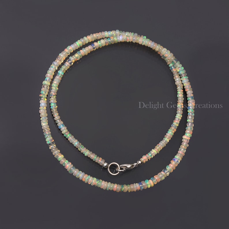 Puede incluir: Un collar delicado hecho con peque&ntilde;as cuentas de &oacute;palo iridiscente. El collar es de color plateado y tiene un cierre de mosquet&oacute;n.