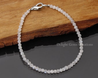 May include: A delicate white moonstone bracelet with a silver clasp. The bracelet is made of small, round beads and is approximately 7 inches in length.