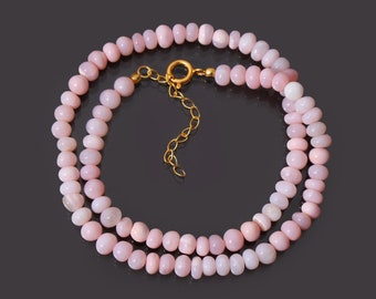 May include: A double strand necklace made of pink opal beads with a gold clasp.