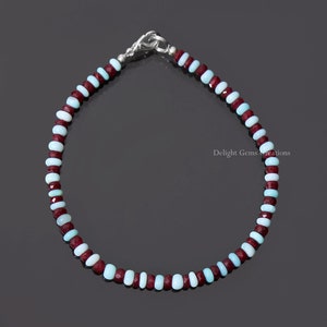 May include: A delicate bracelet made with alternating light blue and burgundy beads. The bracelet has a silver clasp.