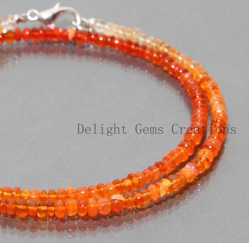 May include: A necklace made of orange and yellow opal beads. The necklace is made of two strands of beads and has a silver clasp.