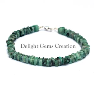 May include: A green emerald gemstone bracelet with a silver clasp. The bracelet is made of square-shaped beads.