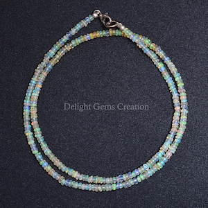 May include: A double strand necklace made of iridescent white opal beads. The necklace is secured with a silver clasp.