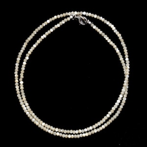 Könnte beinhalten: Eine weiße Perlenkette mit einem silbernen Verschluss. Die Kette besteht aus kleinen, runden Perlen und ist etwa 46 cm lang.