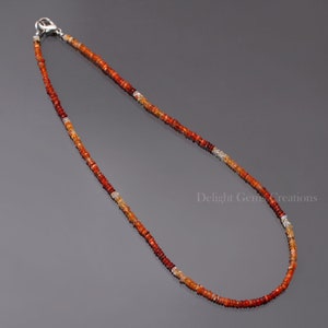 Puede incluir: Un collar delicado hecho con peque&ntilde;as cuentas redondas de piedras preciosas de color naranja, rojo y amarillo. El collar tiene un cierre de plata.