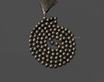 May include: A black pyrite gemstone mala with a tassel. The mala is made of round beads and is approximately 108 beads long.