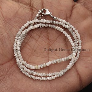 May include: A silver chain necklace made with rough, white diamonds. The necklace is double-stranded and has a silver clasp.