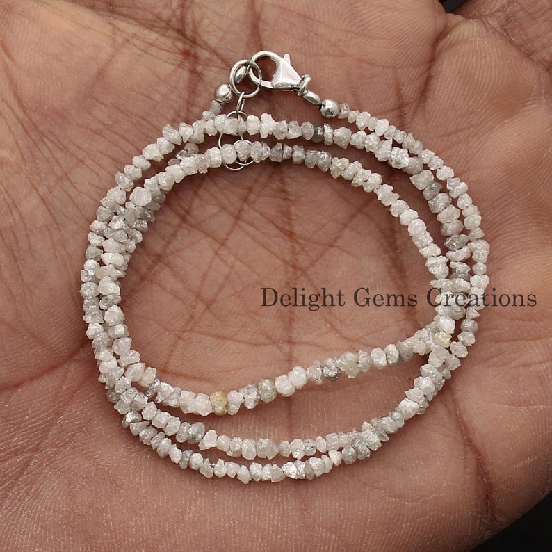 May include: A silver chain necklace made with rough, white diamonds. The necklace is double-stranded and has a silver clasp.