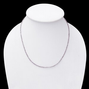 May include: A delicate necklace made of small, light purple beads. The necklace is displayed on a white mannequin bust.