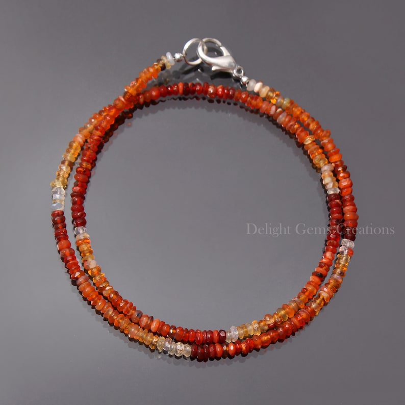 Puede incluir: Un delicado collar de doble cadena hecho con peque&ntilde;as cuentas de &oacute;palo de fuego facetadas, de color naranja, rojo y amarillo. El collar tiene un cierre de plata.