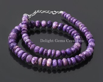 May include: A purple and white gemstone necklace with a silver clasp. The necklace is made of round beads and is layered.