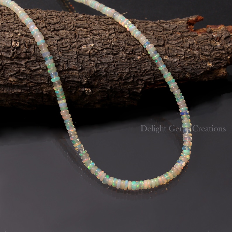 Puede incluir: Un collar de cuentas de &oacute;palo blanco con un brillo delicado e iridiscente. El collar est&aacute; hecho de peque&ntilde;as cuentas redondas y mide aproximadamente 45 cm de largo.
