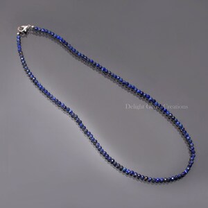May include: A delicate necklace made of small, faceted lapis lazuli beads. The necklace is silver in colour and has a lobster clasp closure.