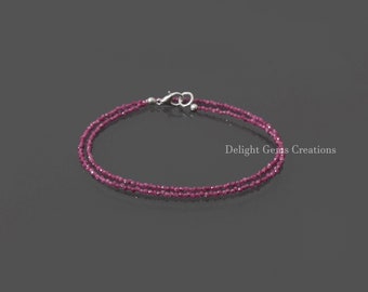 May include: A delicate double-strand bracelet made with small, faceted, ruby red gemstones. The bracelet has a silver clasp.