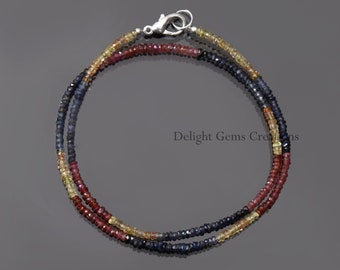 May include: A delicate necklace made with tiny blue, red, and yellow sapphire beads. The necklace is double-stranded and has a silver clasp.