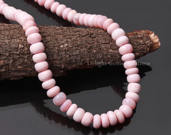 May include: A strand of pink opal beads, approximately 6mm in diameter, strung on a cord. The beads are a pale pink color with a slight iridescent sheen. The beads are displayed on a piece of wood with the text "Delight Gems Creations" visible.