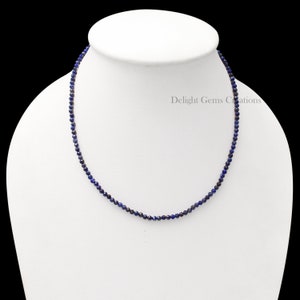 May include: A delicate necklace made of small, dark blue lapis lazuli beads. The necklace is on a white mannequin bust.