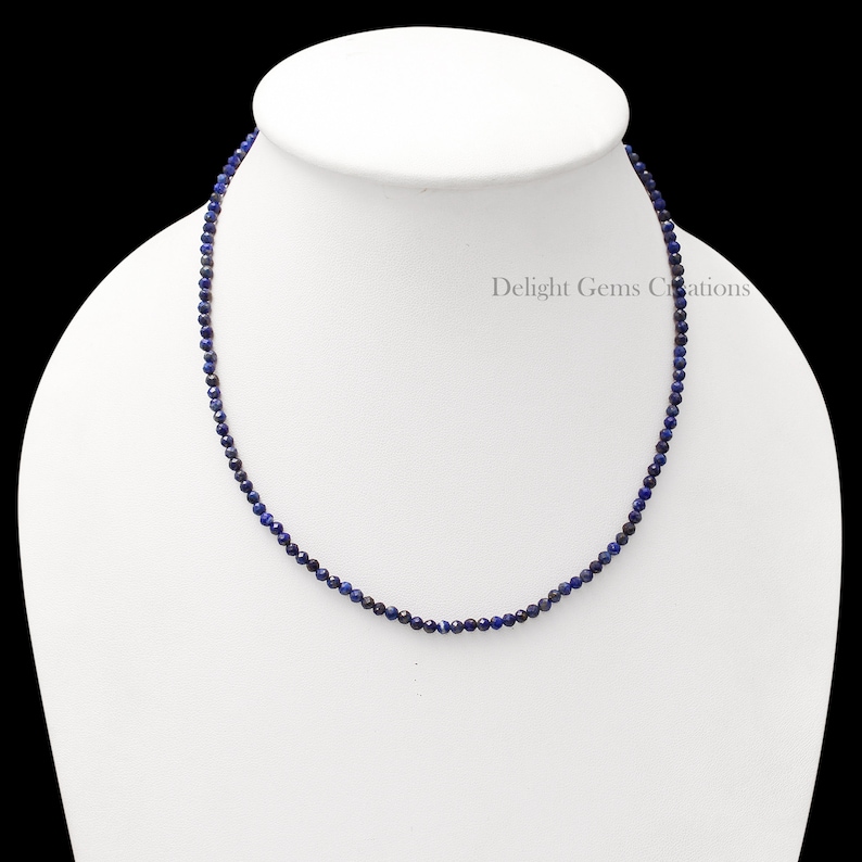 May include: A delicate necklace made of small, dark blue lapis lazuli beads. The necklace is on a white mannequin bust.