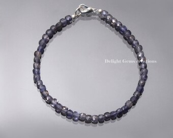 May include: A silver bracelet with a clasp closure, featuring a strand of faceted, dark blue gemstone beads.