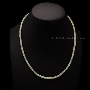 Puede incluir: Un collar delicado hecho de peque&ntilde;as cuentas de &oacute;palo blanco iridiscente. El collar mide aproximadamente 45 cm de largo y est&aacute; enhebrado en una cadena de plata.