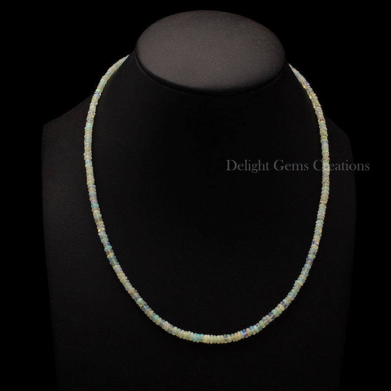Puede incluir: Un collar delicado hecho de peque&ntilde;as cuentas de &oacute;palo blanco iridiscente. El collar mide aproximadamente 45 cm de largo y est&aacute; enhebrado en una cadena de plata.