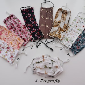 Può includere: Assortimento di mascherine per il viso in vari disegni floreali e fantasia. Le mascherine includono una stampa di libellule, rose rosa e motivi a foglie d'oro. Ogni mascherina ha elastici regolabili.