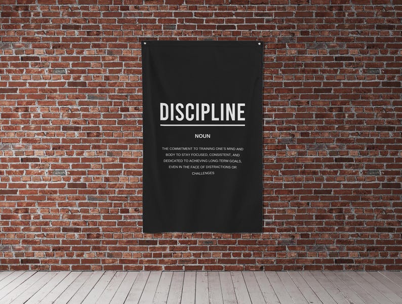 Pu&ograve; includere: Un poster motivazionale in bianco e nero con la parola "DISCIPLINE" in grandi lettere e una definizione della parola sotto. Il poster &egrave; appeso a un muro di mattoni.