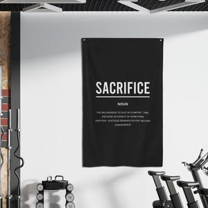 Pu&ograve; includere: Un poster motivazionale in bianco e nero con la parola "SACRIFICE" in grassetto in lettere bianche. La definizione di sacrificio &egrave; scritta sotto in lettere bianche pi&ugrave; piccole: "La volont&agrave; di rinunciare al comfort, al tempo e alla facilit&agrave; nella ricerca di qualcosa di pi&ugrave; grande - il successo richiede uno sforzo che va oltre la convenienza."