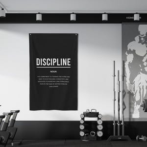 Pu&ograve; includere: Un poster motivazionale in bianco e nero con la parola "DISCIPLINE" in grassetto in lettere bianche. Il poster definisce la disciplina come "l'impegno per allenare la mente e il corpo per rimanere concentrati, coerenti e dedicati al raggiungimento di obiettivi a lungo termine, anche di fronte a distrazioni o sfide."