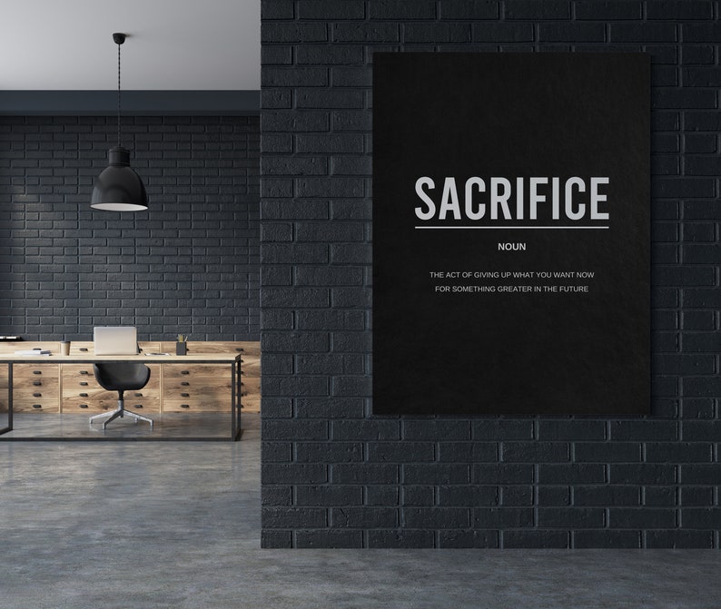 May include: Black and white motivational poster with the word "SACRIFICE" in bold white letters. The text below defines sacrifice as "the act of giving up what you want now for something greater in the future."