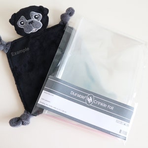 May include: Black plush toy with a pug face and grey felt details. The toy is packaged in a clear plastic bag with a label that reads "Durable Crinkle Foil".
