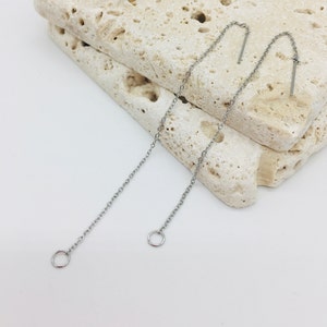 May include: A pair of silver chain earrings with small circular hoops at the bottom and a straight, thin metal bar at the top.