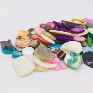 May include: A variety of colorful and iridescent shell buttons in various shapes and sizes, including round, oval, and heart-shaped buttons.