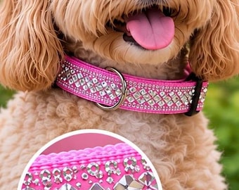 May include: A bright pink dog collar featuring a row of large, square, faceted clear crystals flanked by smaller round rhinestones. The collar includes a silver-toned metal D-ring and a black plastic buckle, shown on a light brown curly-haired dog.