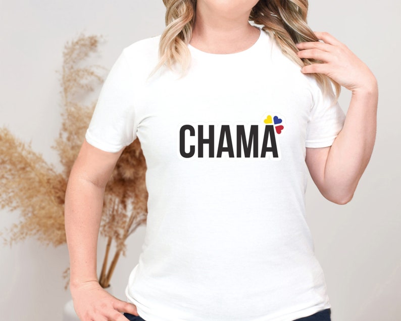 Pu&ograve; includere: Una t-shirt bianca a maniche corte con la parola CHAMA stampata in grassetto nero a lettere maiuscole sul petto. Sopra la lettera A, si trova un piccolo elemento grafico composto da quattro icone a forma di cuore di colore giallo, blu e rosso.