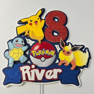 K&ouml;nnte beinhalten: Ein blauer und roter Pokemon-Kuchentopper mit einer roten Zahl 8, einem gelben Pikachu, einem blauen Squirtle, einem braunen Eevee, einem roten Pokeball mit dem Wort "Pokemon" darauf und dem Namen "River" in wei&szlig;en Buchstaben auf einem blauen Banner.