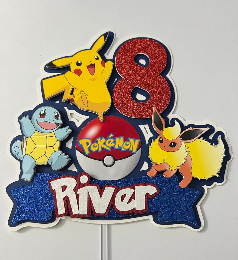 K&ouml;nnte beinhalten: Ein blauer und roter Pokemon-Kuchentopper mit einer roten Zahl 8, einem gelben Pikachu, einem blauen Squirtle, einem braunen Eevee, einem roten Pokeball mit dem Wort "Pokemon" darauf und dem Namen "River" in wei&szlig;en Buchstaben auf einem blauen Banner.