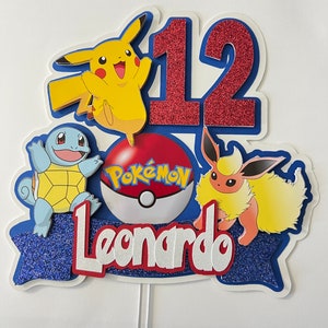 K&ouml;nnte beinhalten: Ein blauer und wei&szlig;er Tortendekor mit einer roten Zahl 12, einem Pok&eacute;ball mit dem Wort Pok&egrave;mon, einem gelben Pikachu, einem blauen Squirtle und einem braunen Eevee. Der Name Leonardo ist in wei&szlig;en Buchstaben auf einem blauen Banner geschrieben.